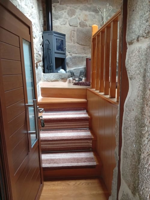 Escalera de madera con tapete a rayas que conduce al interior rústico de la cabaña en Houses by Pilar, Soutomaior