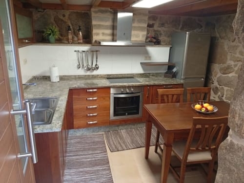 Cocina moderna en la casita O Refuxio da Lua de Houses by Pilar, Soutomaior con armarios de madera, encimeras de granito y comedor