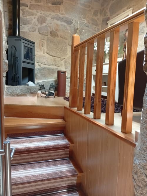 Escalera de madera con alfombra a rayas en casita Houses by Pilar, Soutomaior, con muros de piedra visible