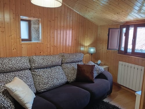 Acogedor salón con paneles de madera en Houses by Pilar, Soutomaior, sofá estampado y vistas a las montañas