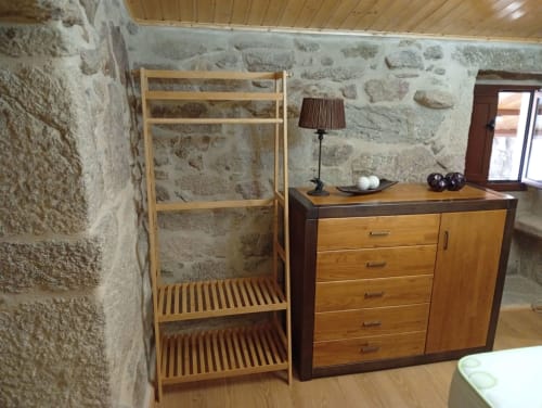 Dormitorio de cabaña rústica en Houses by Pilar con cama de madera, muros de piedra y mobiliario de madera en Soutomaior