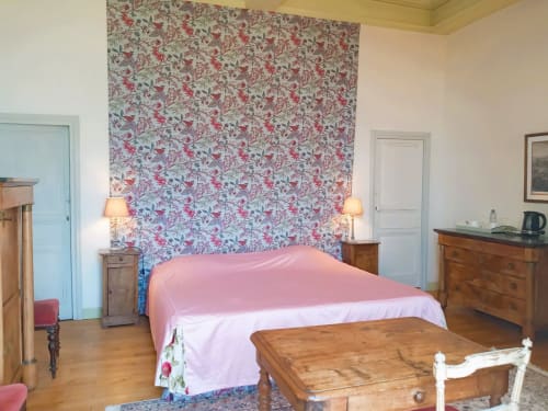 Chambre des Marquis du Château de Gizeux avec literie rose, papier peint fleuri, mobilier en bois et vue sur le jardin