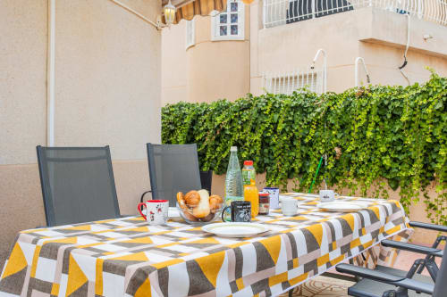 Terraza exterior de Villa Hammely, Cartagena con mesa de desayuno, mantel amarillo a rayas, pastelería fresca y vegetación