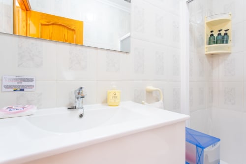 Baño limpio en la cabaña Villa Hammely de Haus Holiday Homes, Cartagena con lavabo blanco, dispensador de jabón amarillo y estantería