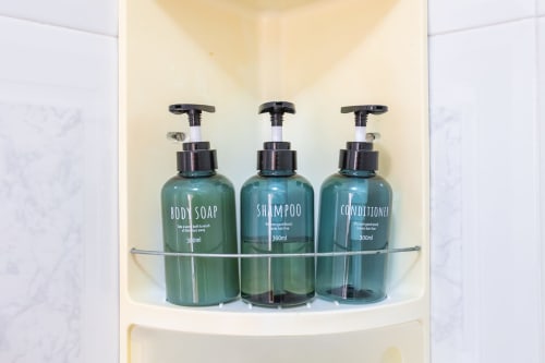Tres botellas dosificadoras de jabón corporal, champú y acondicionador exhibidas en el baño de la villa Haus Holiday Homes