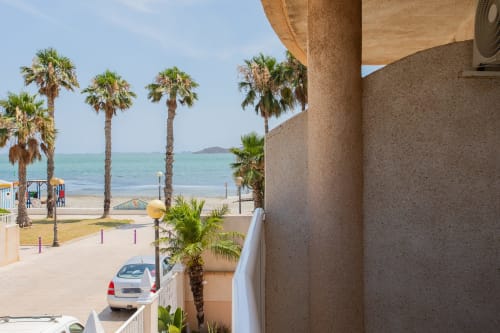 Vista del balcón de Villa Hammely con palmeras y mar turquesa en Cartagena, España