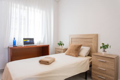 Dormitorio luminoso en Villa Hammely, cabaña de Cartagena con cama de madera, escritorio y vista al mar desde la ventana