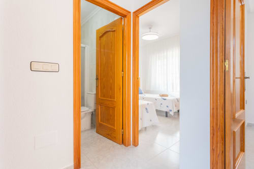 Pasillo luminoso en la casa de huéspedes Villa Hammely, Cartagena, con puertas de madera que abren al dormitorio y baño de paredes blancas