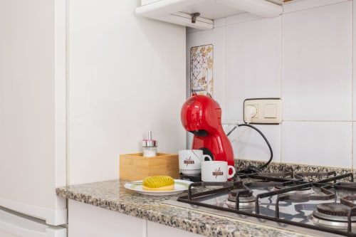 Encimera moderna de la cocina en la villa Hammely de Cartagena con cafetera roja, estufa y encimeros de granito