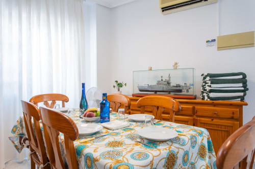 Comedor de la casa Villa Hammely en Cartagena, con sillas de madera, mantelería temática náutica y decoración con vistas al mar.