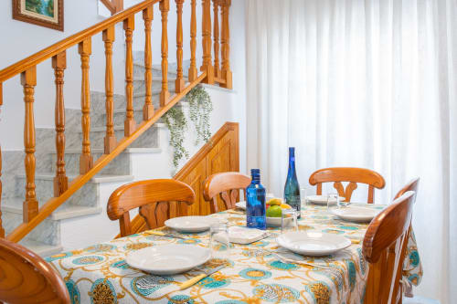 Comedor de la villa Hammely en Cartagena con mesa de madera, sillas y escalera con barandilla ornamental