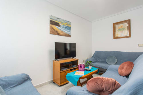 Luminosa sala de estar en Villa Hammely, Cartagena, con sofá azul, mueble de TV de madera, mesita turquesa y cojines coloridos
