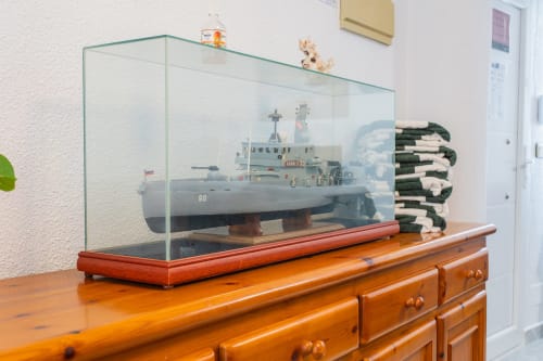 Vitrina de cristal con maqueta de barco militar sobre cómoda de madera en la casita Villa Hammely, Cartagena