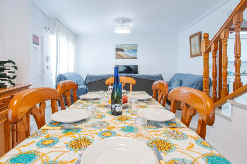 Amplio comedor en Villa Hammely de Cartagena, con sillas de madera, mantel temático marino colorido y sala de estar