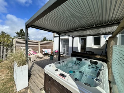 Cottage with hot tub on wooden deck, garden lounge chairs, pergola shelter at La Villa Plein Vent, Barneville-Carteret