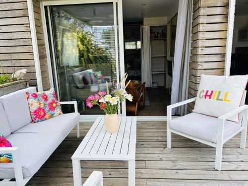 Bright patio seating area at La Villa Plein Vent cottage in Barneville-Carteret with white furniture, colorful pillows, and