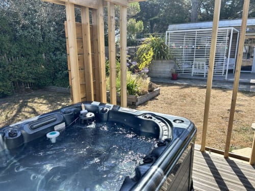 Jacuzzi on wooden deck at La Villa Plein Vent cottage in Barneville-Carteret with garden views