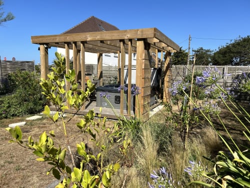 Wooden gazebo with pitched roof in La Bounty cottage garden at La Villa Plein Vent, Barneville-Carteret, surrounded by