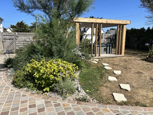 Garden view cottage at La Villa Plein Vent B&B in Barneville-Carteret featuring wooden pergola, yellow flowers, and stone