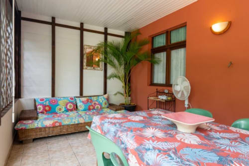 Chambre colorée aux Gîtes Bagatelle à Sainte-Rose avec lits jumeaux, murs orange et plantes tropicales