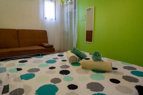 Chambre lumineuse aux Gîtes Bagatelle à Sainte-Rose avec literie à pois colorés, serviettes roulées et murs vert vif