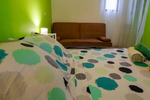 Chambre lumineuse aux Gîtes Bagatelle avec literie à motifs, canapé marron et mur d'accent vert citron à Sainte-Rose