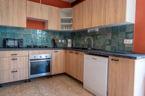 Cuisine moderne aux armoires en bois, dosseret en carrelage turquoise et comptoirs noirs aux Gîtes Bagatelle à Sainte-Rose, Guadeloupe
