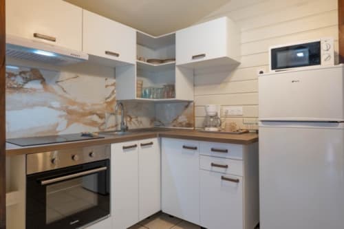 Cuisine moderne aux Gîtes Bagatelle, Sainte-Rose avec placards blancs, crédence en marbre et appareils en acier inoxydable