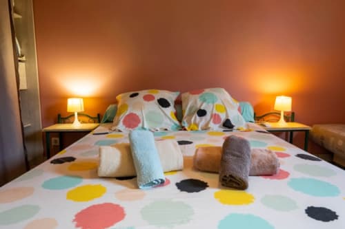 Chambre aux motifs pois colorés aux Gîtes Bagatelle à Sainte-Rose, avec serviettes roulées, lampes jumelles et murs orange chaleureux.