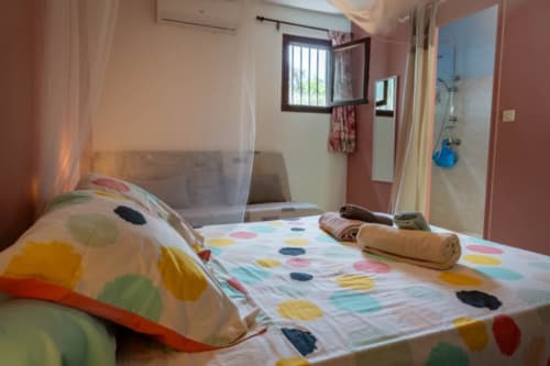 Chambre colorée aux Gîtes Bagatelle avec parure à pois, moustiquaire et salle de bain attenante à Sainte-Rose, Guadeloupe