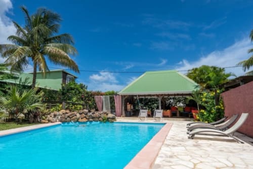 Piscine bleu cristal aux Gîtes Bagatelle à Sainte-Rose, Guadeloupe, avec chaises longues et décor tropical