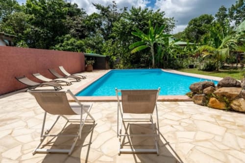 Piscine des Gîtes Bagatelle à Sainte-Rose avec transats et jardins tropicaux
