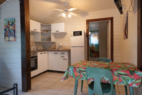 Cottage kitchen and dining area in Gîtes Bagatelle, Sainte-Rose Guadeloupe with equipped kitchen, ceiling fan, and colorful