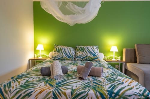 Tropical bedroom at Gîtes Bagatelle with lime green walls, patterned bedding, twin lamps, and ceiling fan in Sainte-Rose,