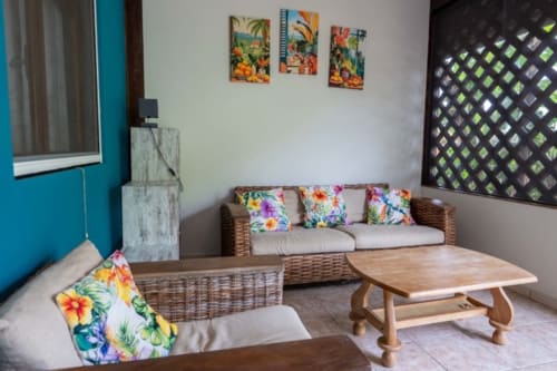 Colorful lounge area with wicker sofa and floral cushions at Gîtes Bagatelle, Guadeloupe cottage rental