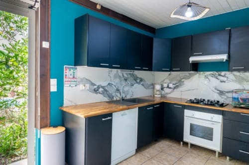 Modern equipped kitchen with turquoise walls, black cabinets, wooden counters, marble backsplash, and stainless steel