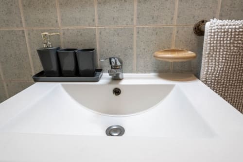 Bathroom sink with black soap dispensers and wooden soap dish at Gîtes Bagatelle, Guadeloupe cottage rental