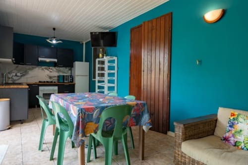 Turquoise kitchen-dining area with green chairs and colorful tablecloth in Guadeloupe cottage rental