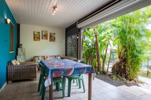 Tropical cottage dining area at Gîtes Bagatelle with lush garden views, table and chairs