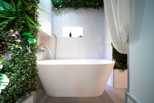 Baño del apartamento Luxer Holidays Glow en Málaga con bañera blanca exenta rodeada de plantas vivas y diseño moderno