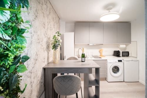 Cocina moderna del apartamento en Málaga con zona de comedor, lavadora-secadora y pared con plantas en la habitación Glow de Luxer Holidays