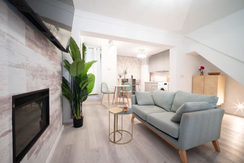 Apartamento Modern Glow en Málaga con sofá gris, chimenea, zona de comedor, cocina y decoración de plantas frescas