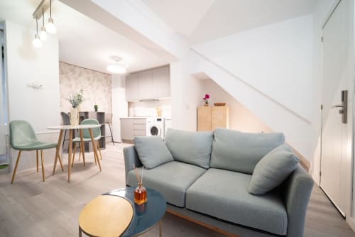 Moderno salón con sofá gris, zona de comedor, cocina y escalera en Luxer Holidays Málaga