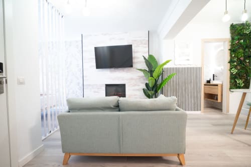 Moderno salón en apartamento Luxer Holidays Glow, Málaga, con sofá gris, TV mural, chimenea y vistas a la ciudad