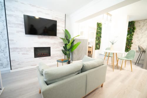 Elegante salón en apartamento Luxer Holidays de Málaga con sofá beige, chimenea, TV empotrada y plantas decorativas