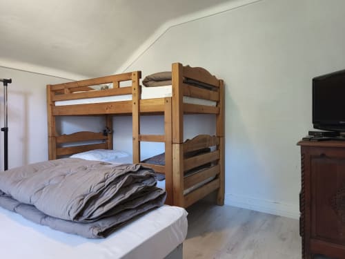 Letti a castello in legno con biancheria bianca nell'appartamento 4 dello Chalet Coste Belle, Ceillac, con TV e vista sulle montagne