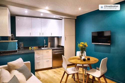Appartement moderne Le Nid à AJOUCADOU Lourmarin avec murs bleu-vert, cuisine, salle à manger et télévision écran plat