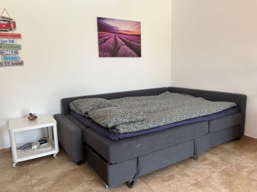 Dark gray sofa bed with patterned bedding in Villa Estrella Polar apartment, Tahiche, with white nightstand and lavender