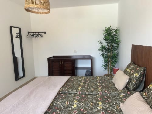 Bright bedroom at Villa Estrella Polar with floral bedding, dark wood furniture, and decorative plant in Tahiche