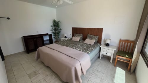 Spacious bedroom at Villa Estrella Polar apartment in Tahiche with wood bed frame, twin nightstands, and pool view